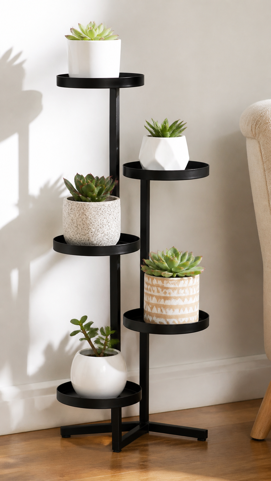 A professional photograph of a modern black metal plant stand with offset circular shelves holding various small pott...